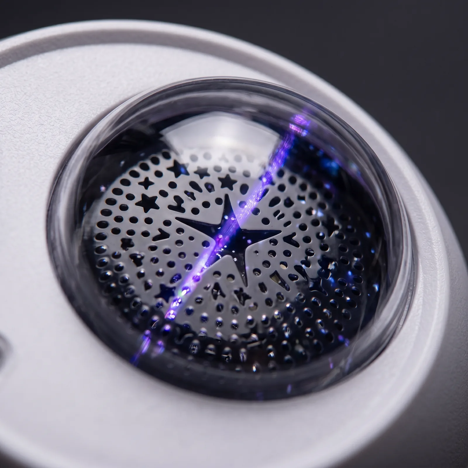 Macro of the star-pierced projection dome, violet laser light inside